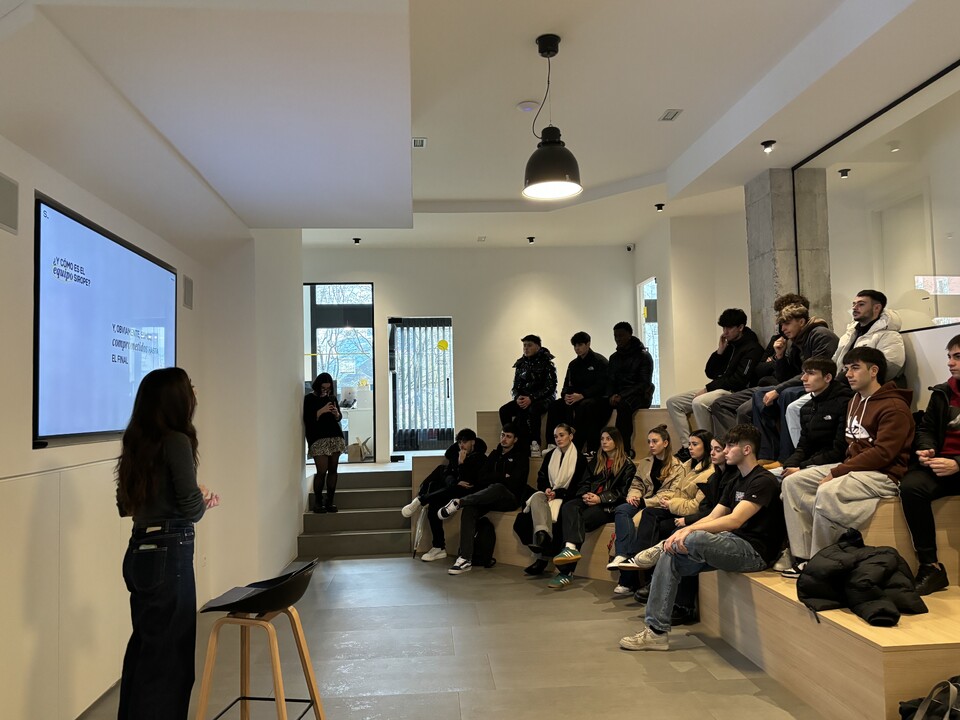 Ikasleak jesarrita, agentziako arduradun bat haien funtzionamendua azaltzen duen bitartean